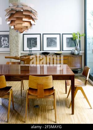 Essbereich mit Holzskulptur auf Tisch mit Stühlen, Sideboard und modernem Licht in spanischen Wohnhäusern. Stockfoto