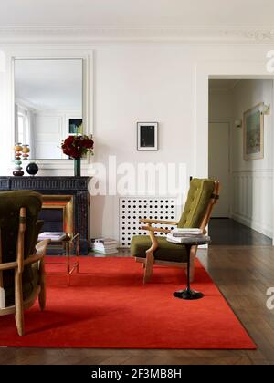 Wohnbereich mit Kamin, Spiegel und Sesseln in französischem Wohnhaus. Stockfoto