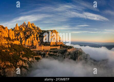 Montserrat und Kloster Montserrat bei Sonnenaufgang mit einem Meer aus Wolken vom Aussichtspunkt Creu de Sant Miquel aus gesehen (Provinz Barcelona, Katalonien, Spanien) Stockfoto
