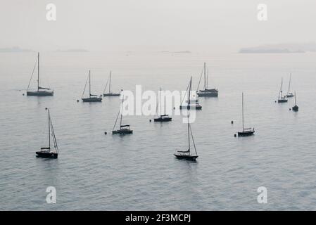 Silhouetten von verankerten Segelbooten im Nebel Stockfoto