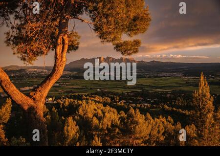 Blick über Pla de Bages und Montserrat im Hintergrund bei einem Frühlingsuntergang. Von Castellnou de Bages aus gesehen (Provinz Barcelona, Katalonien, Spanien) Stockfoto