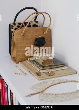 Leder und Tierhaut Damen Handtaschen mit Büchern und zarte Spitze Schmuck auf Bücherregal im Wohnhaus, Niederlande. Stockfoto