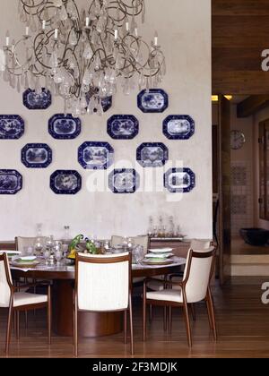 Set Tisch mit Kristall Kronleuchter und montiert china Platten mit offener Tür in Wohnhaus, Brasilien. Stockfoto