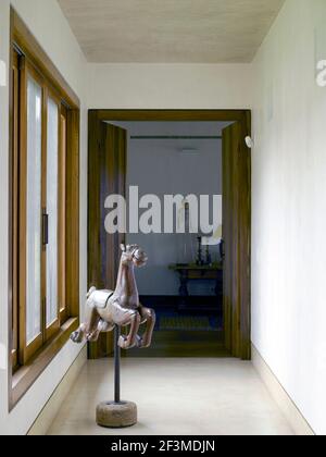 Flur mit Schaukelpferd und Blick durch offene Doppeltüren zum Schlafzimmer im Wohnhaus, Brasilien. Stockfoto