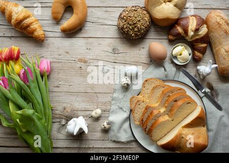 Köstliches frisches osterfrühstück mit verschiedenen ostergebäck und ostern Brot und schöne bunte Blumen Tulpen mit Dekoration Hase und Eier auf Stockfoto