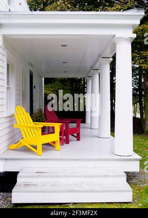 Rote und gelbe Holzstühle auf weißer Veranda in Larson, New York, USA Stockfoto