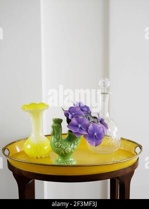 Gelbes Tablett mit Glasflasche und zwei Vasen auf kleinem Tisch im Wohnhaus, Dänemark Stockfoto