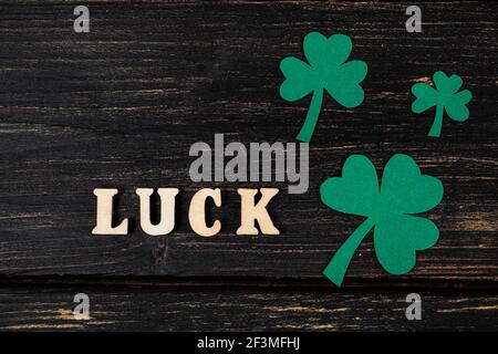 Flatlay für St. Patrick's Day. Kleeblätter auf dunklem Holzhintergrund. Fröhlicher irischer Feiertag, Symbole von Viel Glück. Stockfoto