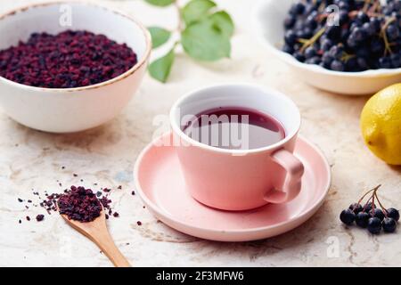 Aronia-Beerentee in einer Tasse. Getrocknete Aroniabeeren werden häufig verwendet, um antioxidationsreichen Kräutertee zu machen. Stockfoto