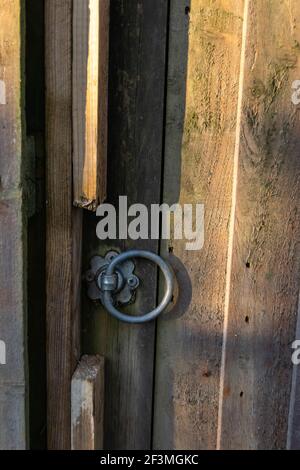 Nahaufnahme Gartentür mit rundem Metallknopf, Holztür mit kreisförmigem Griff, alter Holzzaun mit verschlossener Tür Stockfoto