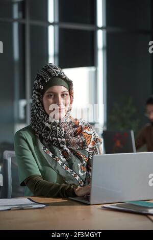 Porträt einer jungen Frau in Hijab Blick auf die Kamera während Arbeiten an ihrem Arbeitsplatz im Büro Stockfoto