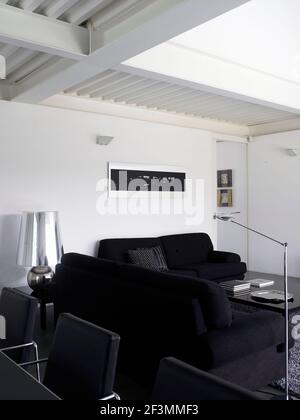 Schwarze Sofas um den Couchtisch im weißen Wohnzimmer Spanische Heimat Stockfoto
