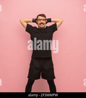 Lächelnder Mann in schwarzer Sportkleidung und Brille isoliert auf rosa Hintergrund. Stockfoto