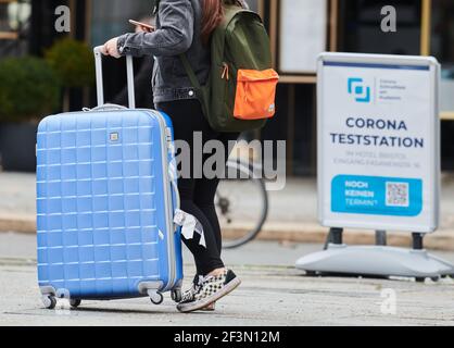 Berlin, Deutschland. März 2021, 17th. Eine Frau geht mit einem rollenden Koffer am Kuhdamm entlang. Auf dem Schild steht 'Corona -Teststation'. Quelle: Annette Riedl/dpa/Alamy Live News Stockfoto