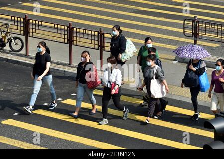 Hongkong, China. März 2021, 17th. Menschen mit Gesichtsmasken überqueren eine Straße in Hongkong, Südchina, 17. März 2021. Das Zentrum für Gesundheitsschutz in Hongkong (CHP) meldete am Mittwoch 11 weitere bestätigte Fälle von COVID-19, insgesamt 11.340. Kredit: Lo Ping Fai/Xinhua/Alamy Live Nachrichten Stockfoto