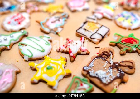 Handverzierte gebackene Lebkuchen in verschiedenen Formen, auf Backpapier angeordnet. Stockfoto