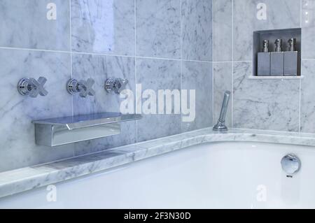 Verchromte Armatur in Marmorfliesen über der Badewanne Stockfoto