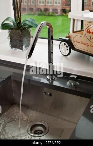 Wasser läuft aus Chrom Wasserhahn in Waschbecken, Großbritannien zu Hause Stockfoto