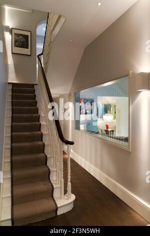Innenarchitekt im Besitz Familienhaus in Wandsworth. Treppe mit oben-unten Feuerzeugen und Fenster durch das Wohnzimmer Stockfoto