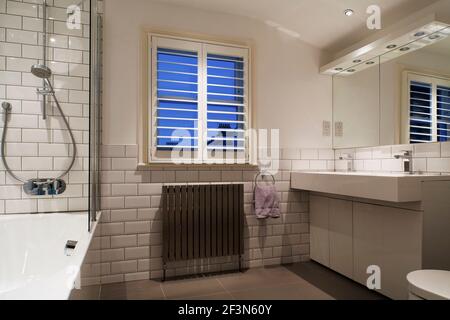Innenarchitekt im Besitz Familienhaus in Wandsworth. Familienbadezimmer mit gefliesten Wänden, Doppelwaschbecken, Badewanne mit Einbaudusche Stockfoto