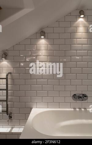Innenarchitekt im Besitz Familienhaus in Wandsworth. Gästebad mit gefliesten Wänden, beheiztem Handtuchhalter, Daunenanzündern und Badewanne Stockfoto