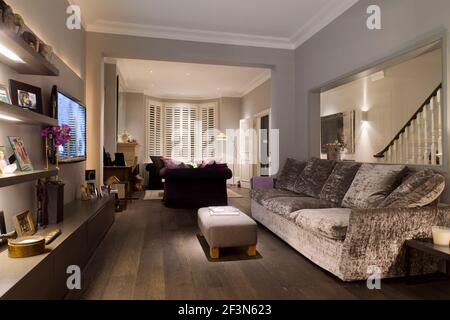 Innenarchitekt im Besitz Familienhaus in Wandsworth. Geräumiges Doppel-Wohnzimmer, TV-Bereich mit integriertem Regal mit eingelassenen Streifen-LIGH Stockfoto