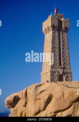 Cote de Granit Rose. Leuchtturm. Rosafarbener Granitturm. Geschnitzt. Glatte Felsunterlage. Sitzende Frau. Stockfoto