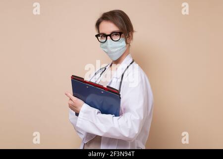 Weibliche Arzt mittleren Alters in medizinische Maske Blick auf Kamera. Studioaufnahme Stockfoto