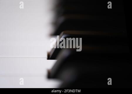 Schwarz-weiße Klaviertasten Seitenansicht. Die schwarzen Tasten werden als Sharps oder Flats bezeichnet. Fokus auf die schwarze Taste in der Bildmitte, geringe Tiefe von f Stockfoto