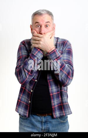Studio Porträt von reifen bärtigen Mann in legerer Kleidung suchen schockiert, während die Abdeckung Mund mit beiden Händen. Das ist unglaublich. Sagen Sie es. Wirklich. Sie Stockfoto