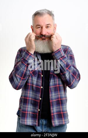 Studio Porträt von reifen bärtigen Mann in lässiger Kleidung wirbeln Sein Schnurrbart und Blick auf die Kamera über weißem Hintergrund Stockfoto