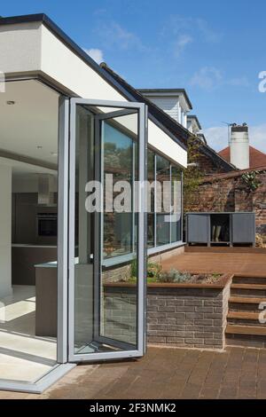 Rückseite des Hauses, und Bi-Fold Türen aus der Küche auf die Terrasse.  Glaswände Panel.  Ein modernes Einfamilienhaus. Stockfoto