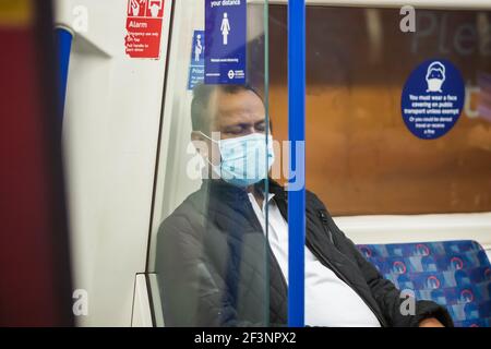 London, Großbritannien - 26. Februar 2021 - EIN Mann, der während der Pandemie von Covid-19 auf der Londoner U-Bahn eine Gesichtsmaske trägt Stockfoto