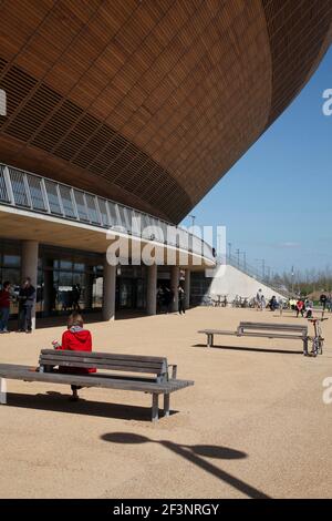 Sitzende Frau in rot vor Velodrom. Stockfoto