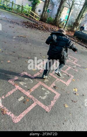 Grundschüler spielen hopfscotch auf einem Schulhof während ihrer Pause vom Unterricht. Stockfoto