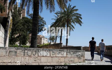 Palma, Spanien. März 2021, 17th. Zwei Männer gehen an einem Graffiti vorbei, das sagt: "Touristen Geh nach Hause." Quelle: Clara Margais/dpa/Alamy Live News Stockfoto