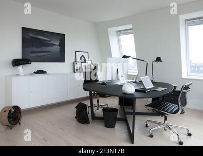 Kein Unsinn, moderne Wohnung in Kopenhagen. Ein monochromes Dekor mit dezenten Farbakzenten. Ein Schreibtisch und Stühle. Stockfoto