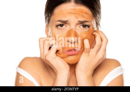 Junge enttäuschte Frau mit falschen Make-up-Basis auf ihrem Gesicht Auf weißem Hintergrund Stockfoto