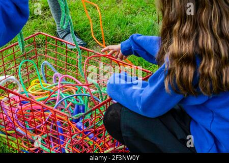 Zwei Schulkinder mit einem Korb aus Springseilen werden nach einer Pause vom Unterricht wieder in die Schule gebracht. Stockfoto