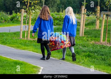 Zwei Schulkinder mit einem Korb aus Springseilen werden nach einer Pause vom Unterricht wieder in die Schule gebracht. Stockfoto