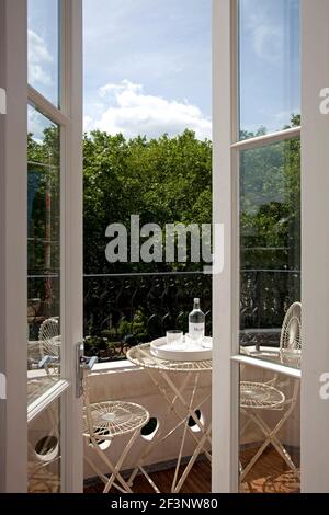 Knightsbridge Apartment, London. Blick aus dem Fenster Bäume des Parks Reifen. Tisch und Stühle auf einer kleinen Terrasse. Stockfoto