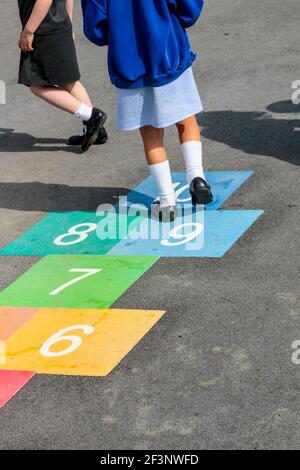 Grundschüler spielen hopfscotch auf einem Schulhof während ihrer Pause vom Unterricht. Stockfoto