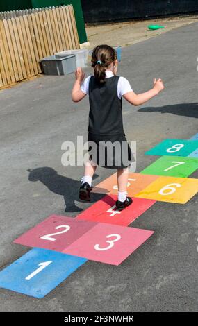 Grundschüler spielen hopfscotch auf einem Schulhof während ihrer Pause vom Unterricht. Stockfoto