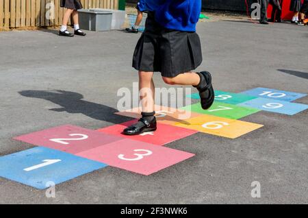 Grundschüler spielen hopfscotch auf einem Schulhof während ihrer Pause vom Unterricht. Stockfoto