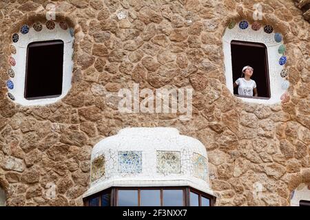 Ein Tourist blickt aus einem Fenster des Service-Pavillons im Park Güell, Barcelona, Spanien, 1900-14. Stockfoto