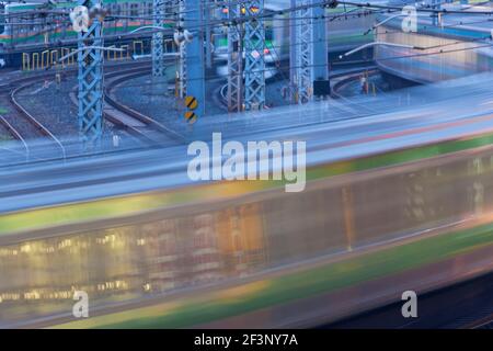 Pendlerzüge pendeln um die Gleise, die in die Ueno-Station in Tokio, Japan, in dieser Teleaufnahme mit einer langsamen Verschlusszeit, die die b erzeugt Stockfoto