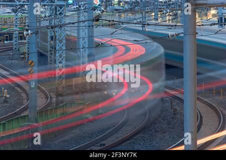 Pendlerzüge pendeln um die Gleise, die in die Ueno-Station in Tokio, Japan, in dieser Teleaufnahme mit einer langsamen Verschlusszeit, die die b erzeugt Stockfoto