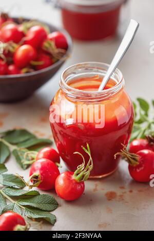 Ein Glas Rosenhüftgelee und frische Hagebutten auf dem Tisch. Stockfoto