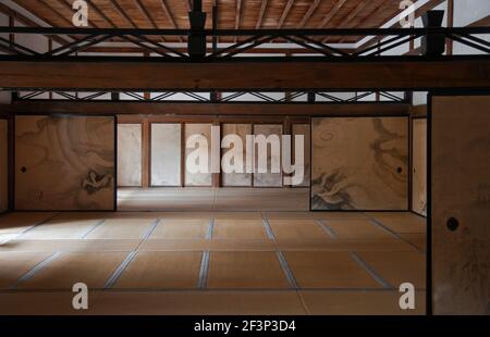 Eine Innenansicht mit natürlichem Licht zeigt die Tatami-Matte Zimmer mit handbemalten Fusuma-Schiebetüren und Naturholzdecke In der Kuri-Haupthalle A Stockfoto