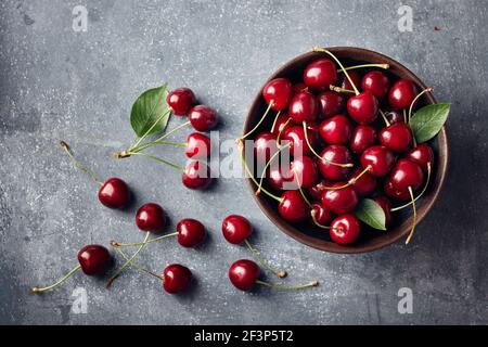 Kirschen in einer kleinen Schüssel und verstreut um den Tisch. Stockfoto